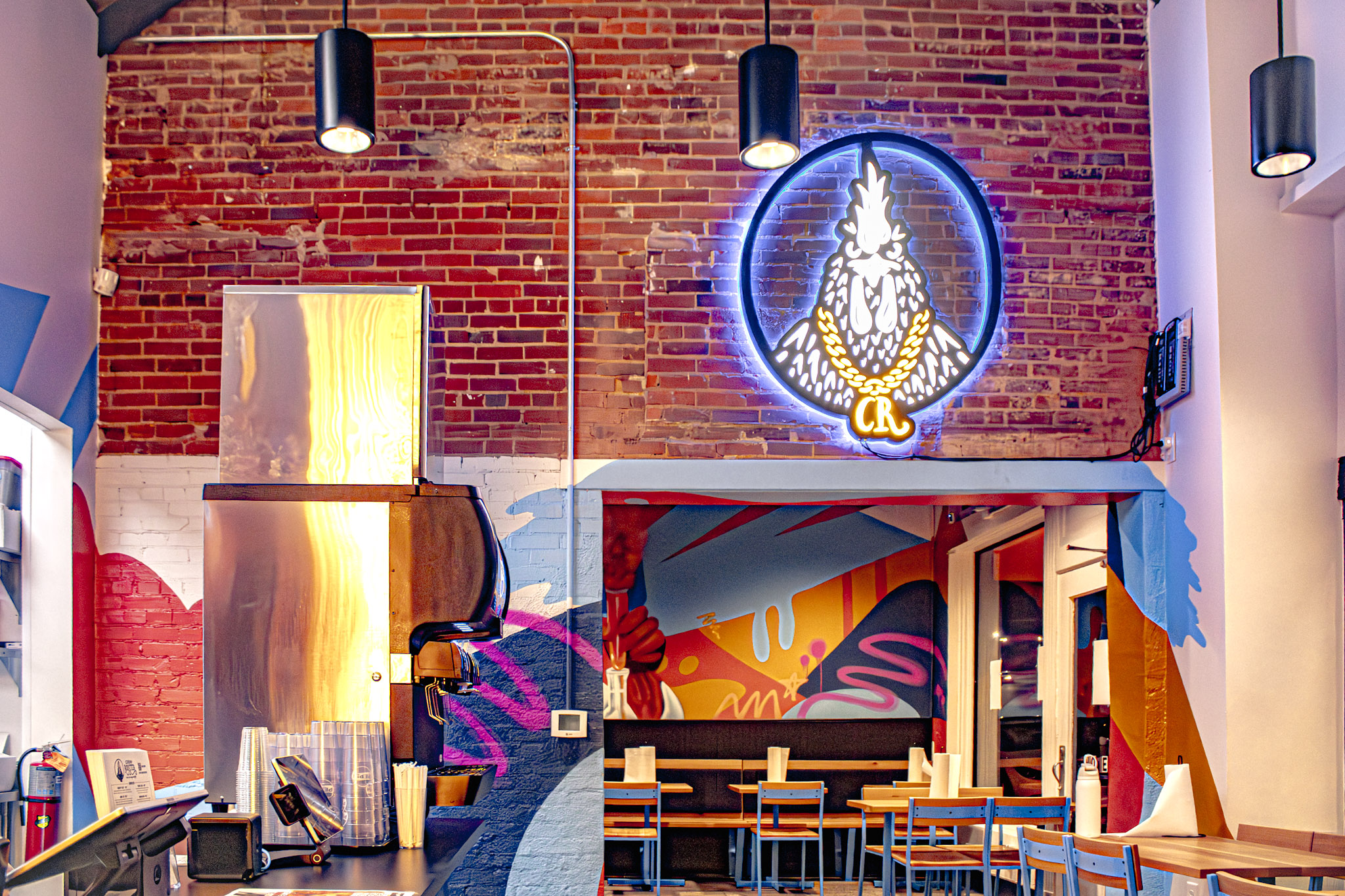 Exposed brick, neon logo and mural-covered walls inside Cocky Rooster Columbia SC