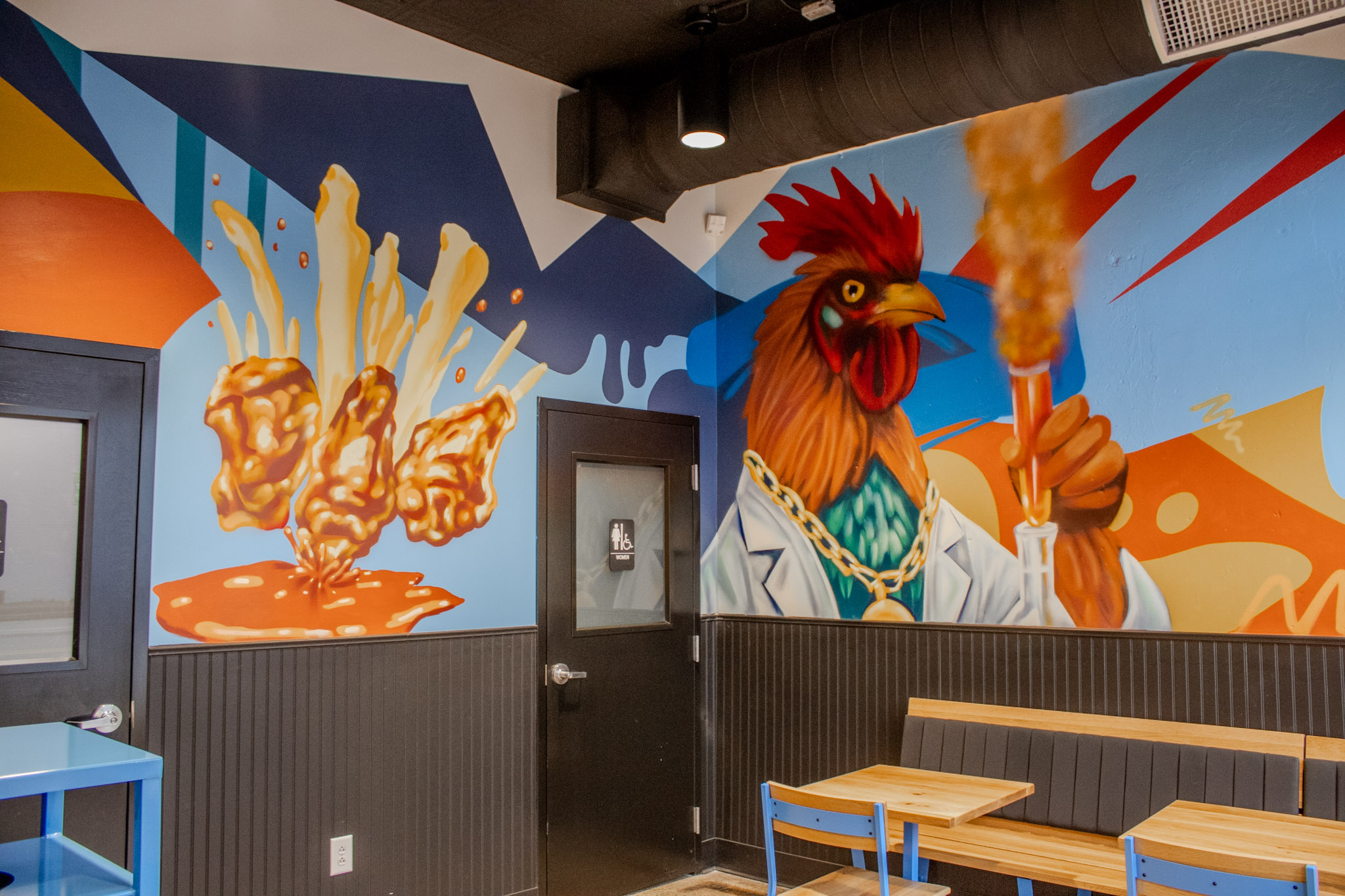 Dining room mural of a rooster in a lab coat pouring sauce over wings, Cocky Rooster Columbia SC