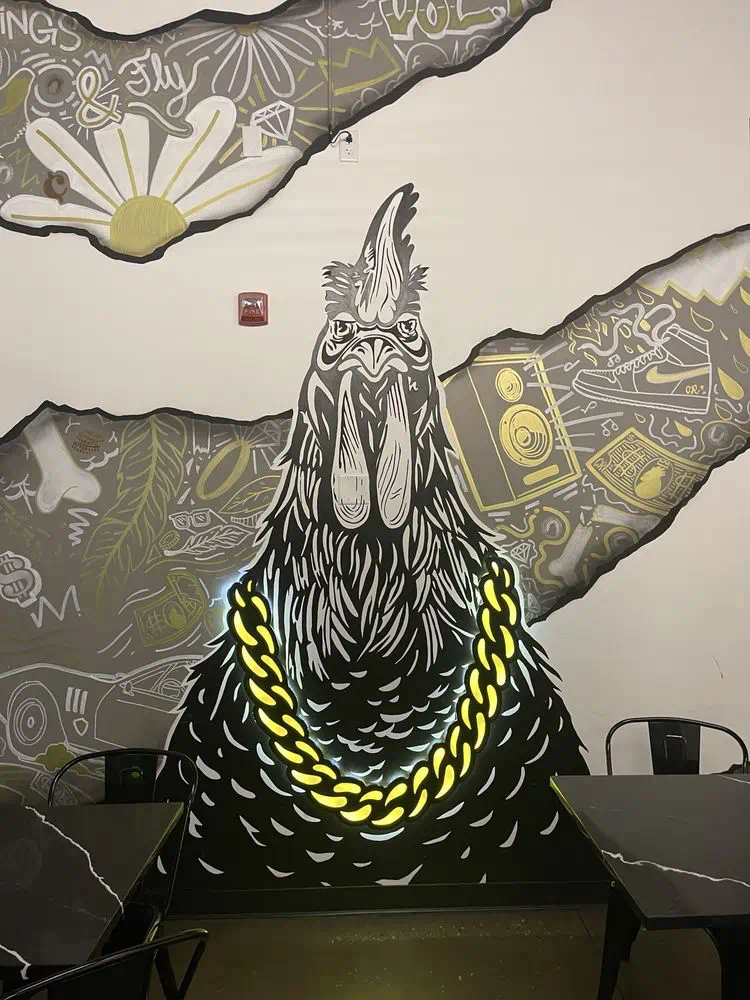 Rooster with a gold chain mural filling the wall by the tables