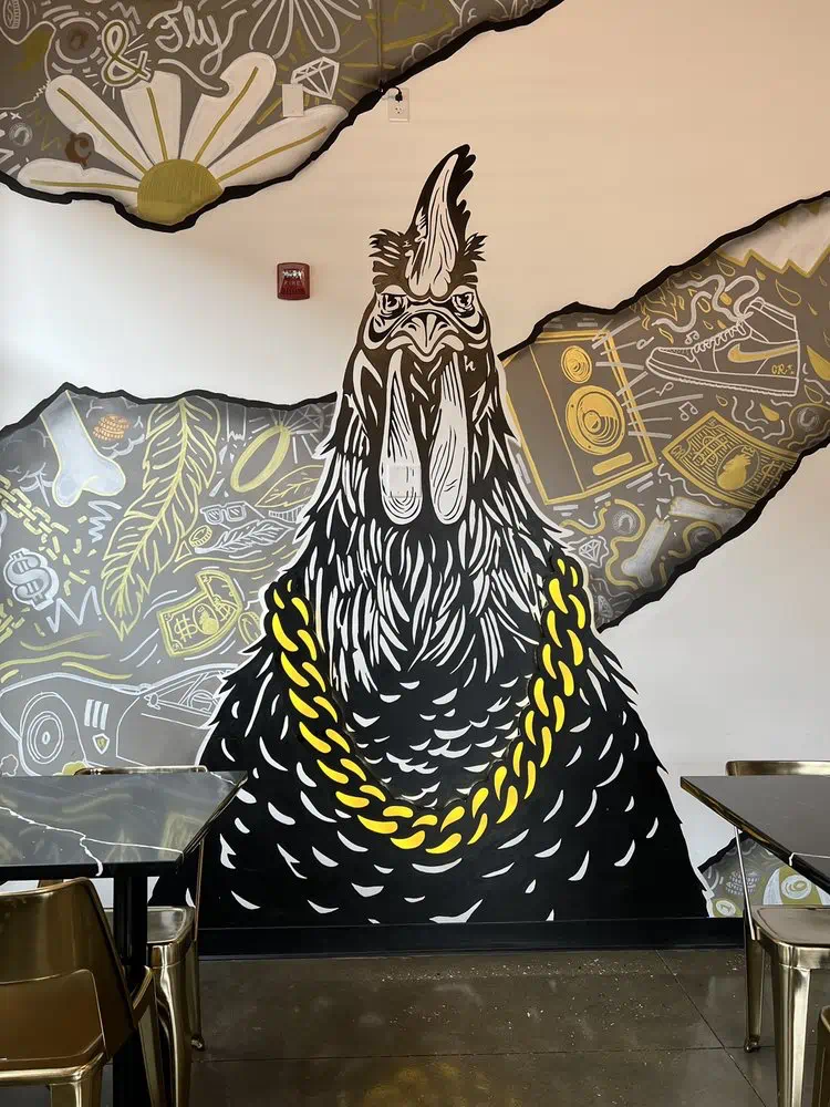 Gold-chain rooster mural on the wall behind the tables