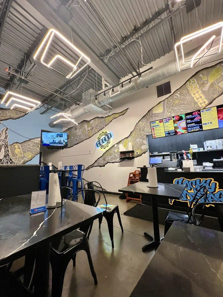 Dining room with TVs, the neon Cocky sign and mural-covered walls