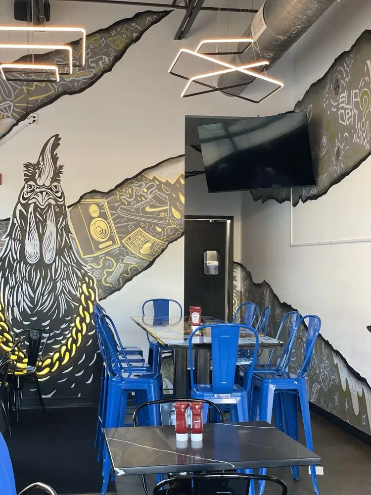 Rooster mural beside the blue chairs and tables near the restroom door