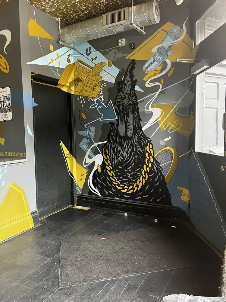 Black rooster with a gold chain mural in the entryway at Cocky Rooster The Fan