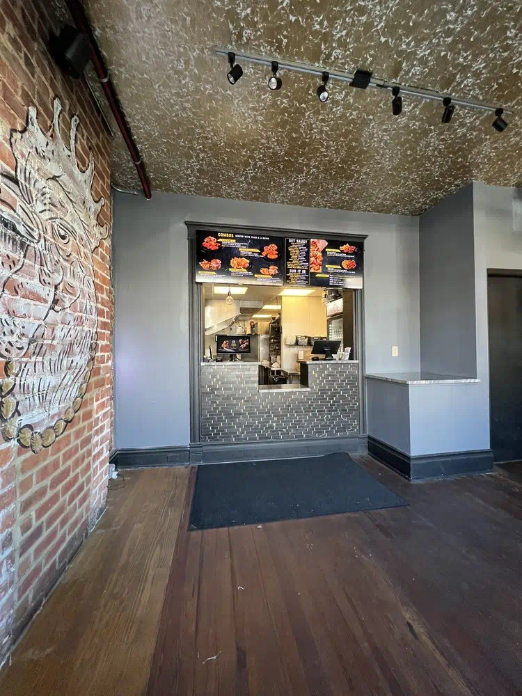Order window with the menu boards above and the exposed-brick wall beside it inside Cocky Rooster The Fan