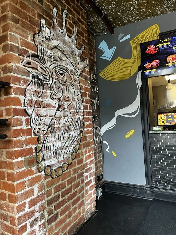 Rooster mural painted on the exposed red brick beside the order window