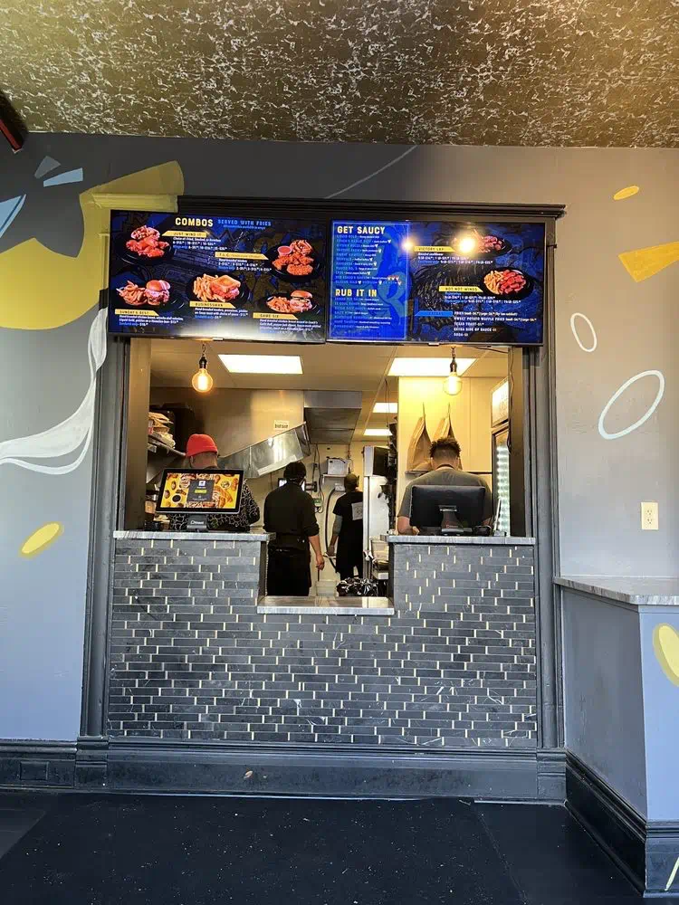 The kitchen crew at work behind the order window, menu boards lit above